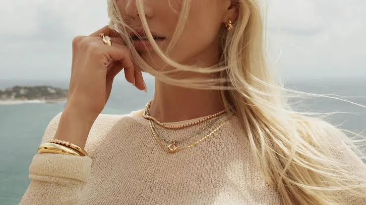 Layered gold necklaces and bracelets worn on camera